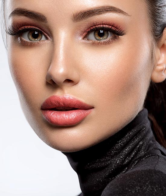 A woman with a neutral expression, wearing makeup and a black turtleneck, against a white background.