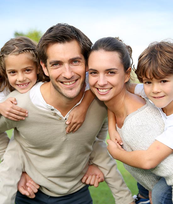 A family of six, including a man and woman with four children, posing for a photograph outdoors.