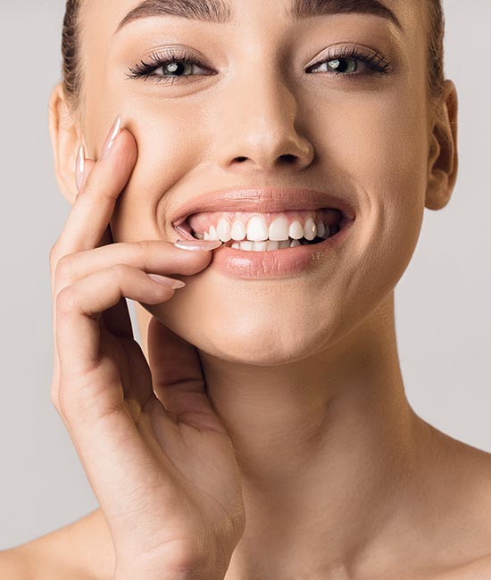 The image features a close-up of a woman with a radiant smile, showcasing her teeth and the action of brushing them.